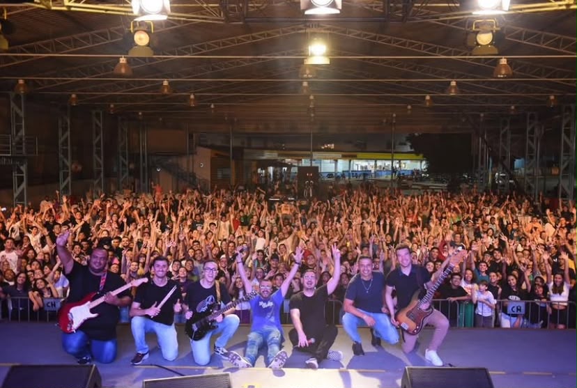 Banda se agachando no palco diante de multidão de braços erguidos