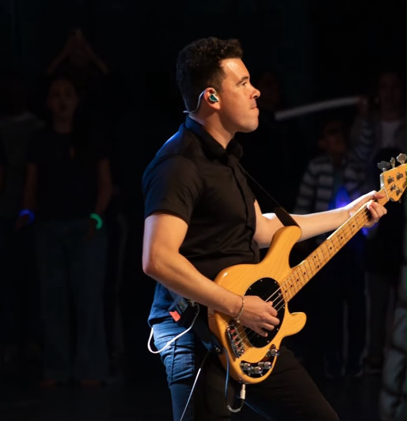 Samuel tocando baixo no palco durante show
