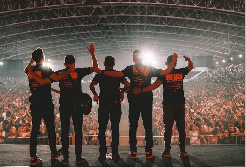 A banda de costas diante de uma multidão de fãs